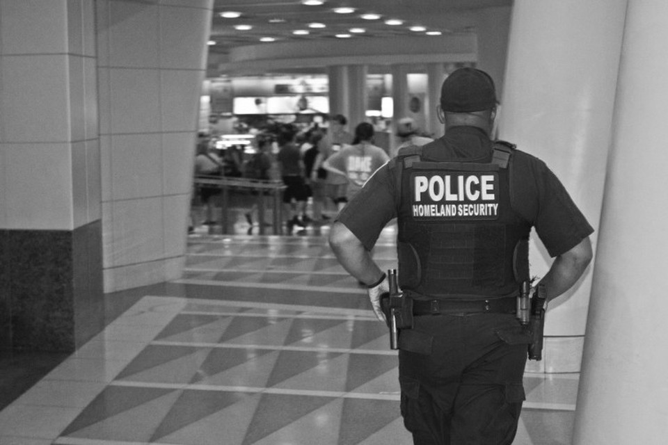 Homeland security officer walking through a hall toward a security checkpoint.