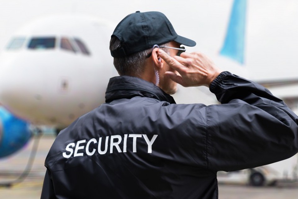 A security specialist at an airport communicates with colleagues via an earpiece.
