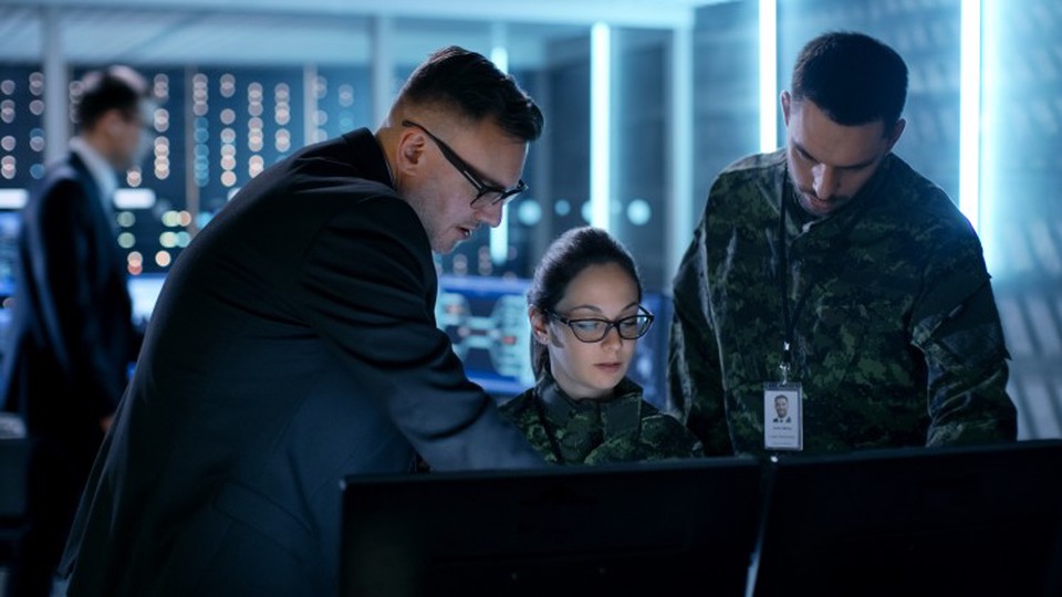 A group of counterterrorism officials reviews information on a computer monitor.