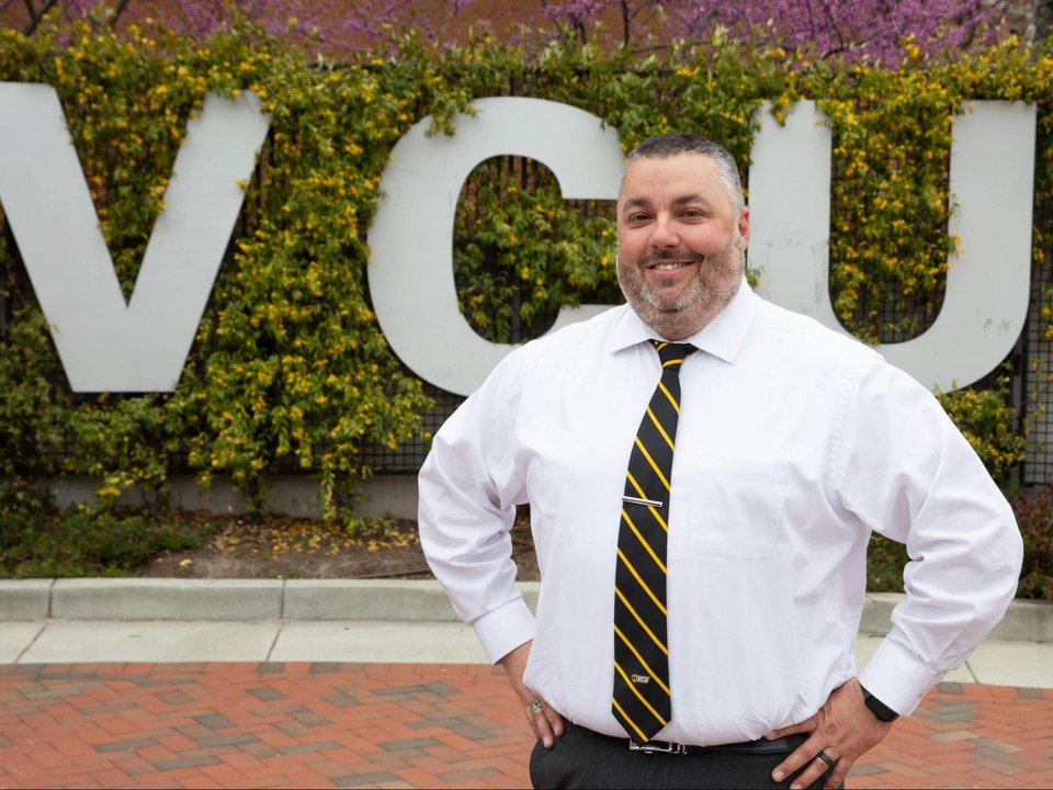 VCU HSEP student James Matt Leicester stands in front of a VCU sign on campus.